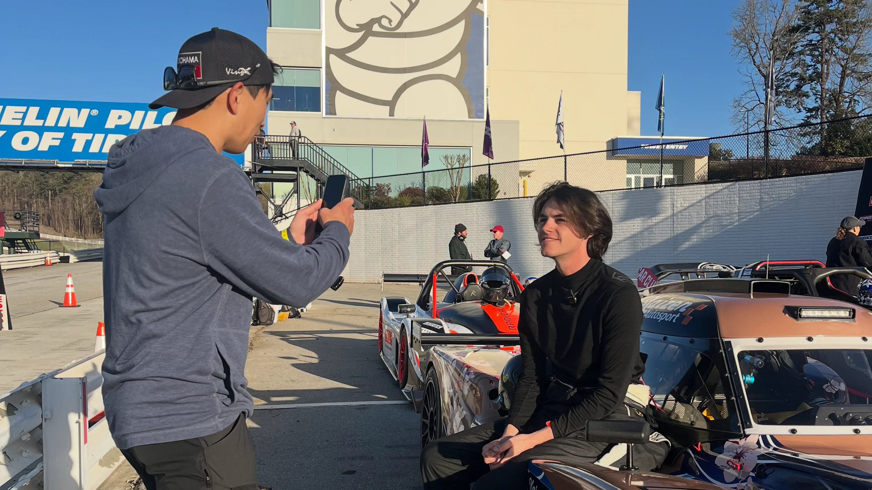 A creator filming a driver and race car at the track